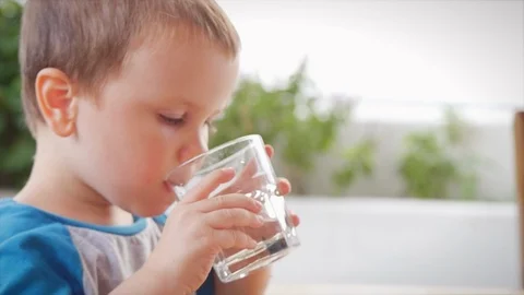 Cute baby boy drinking a glass of water in a cafe. Slow motion little boy Stock Footage