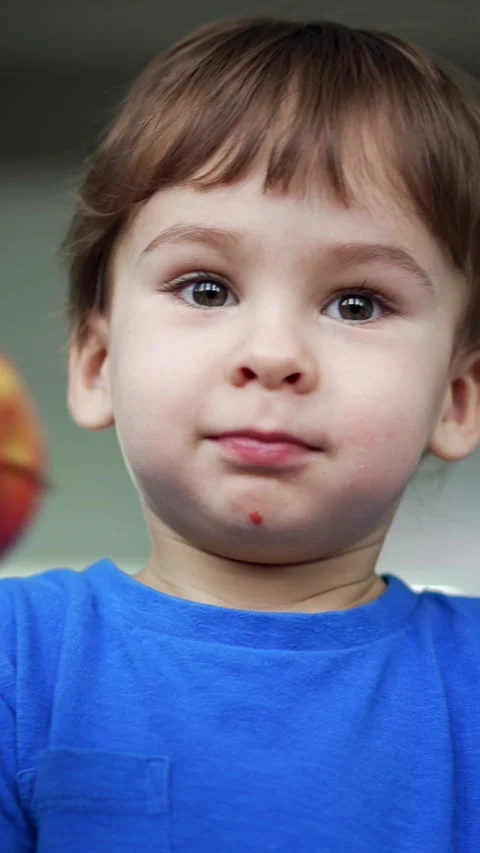 Cute baby boy holding two apples in hands. Kid bumps the fruit and then takes a Stock Footage 342249227