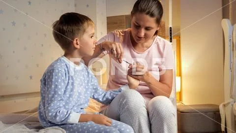 Cute baby boy looking how his mother is cutting his fingernails with ...