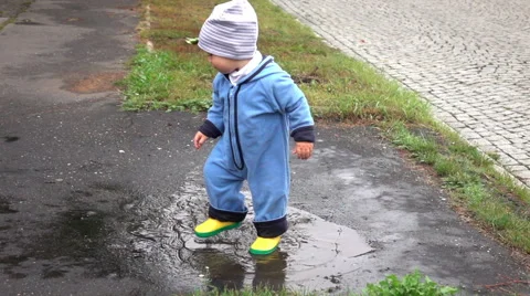 Cute baby boy is playing in puddle, slow motion Stock Footage 67689626