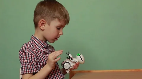 Cute baby boy programs interactive toy robot. Teaches the robot to speak. Stock Footage 125183604