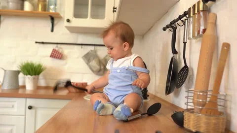 Cute baby boy sitting and playing in the kitchen Stock Footage 135882553