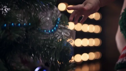 Cute baby boy in striped cap shoots a green ball toy from a Christmas tree Stock Footage 86530490