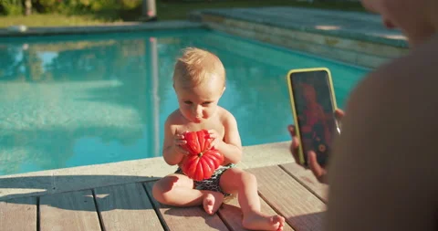 Cute baby boy testing tomato first time his life sitting outside. Young mother Stock-Footage 202508232