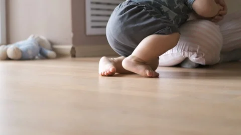 Cute baby doing the first steps and falls in slow motion at home near his mother Stock Footage 126492638