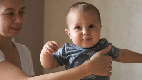 Cute baby doing the first steps and falls in slow motion at home near his mother Stock Footage 126493375