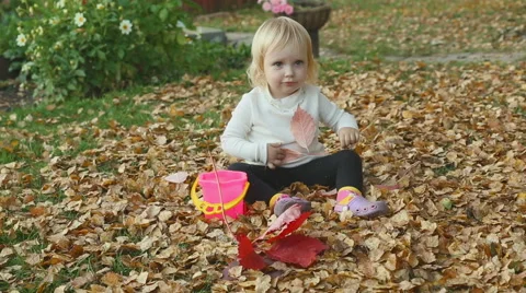 Cute baby girl playing with leaves in autumn Stock Footage