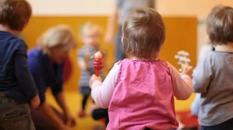 Cute baby girl plays rattle in kindergarten Stock Footage