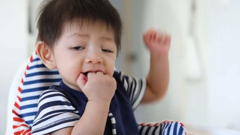 Cute baby kid using finger hand in mouth itchy gum Stock Footage 80923754