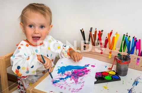 Cute baby is painting with paintbrush on white paper Stock Photos