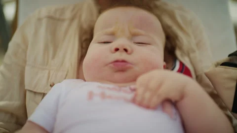 Cute baby with redhead making a funny face, relaxing in adult person's arms, Stock-Footage 339831255