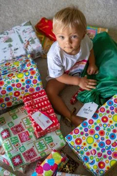 A Cute Baby Sitting With Christmas Presents Stock Photos