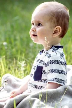 Cute bady boy looking surprised with big beautiful eyes sitting on grass outdoor Stock Photos