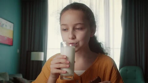 Cute beautiful child drinking milk and eating cracker cookies at home. Healthy Stock Footage 247363313