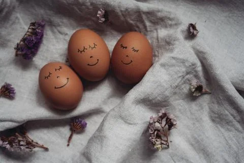 Cute beautiful Easter eggs with a painted face and dried flowers on the linen Stock Photos