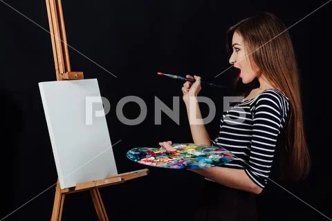 Cute beautiful girl artist painting a picture on canvas an easel. Space for text Stock Photos