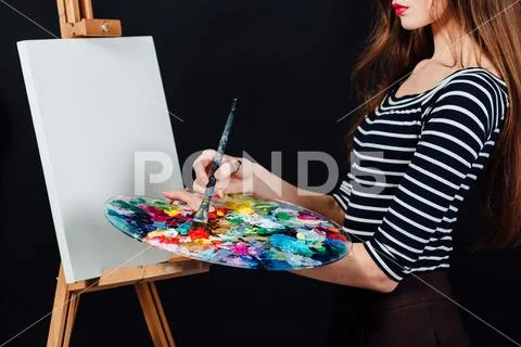 Cute beautiful girl artist painting a picture on canvas an easel. Space for text Stock Photos