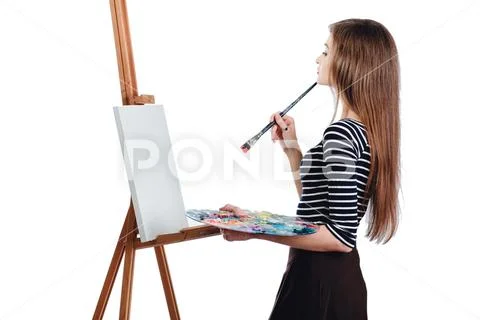 Cute beautiful girl artist painting a picture on canvas easel. Space for text Stock Photos