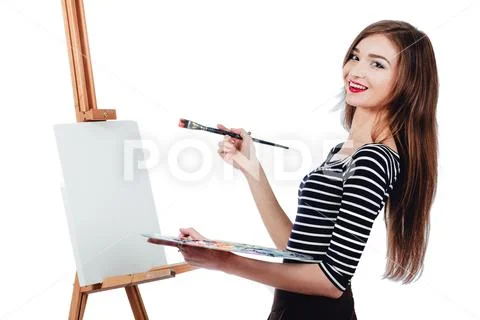Cute beautiful girl artist painting a picture on canvas easel. Space for text Stock Photos