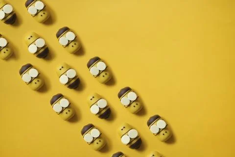 Cute Bee cake pops pattern. yellow cartoon bees fly in a row on a yellow paper Stock Photos