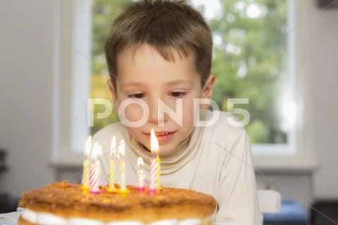 Cute Birthday Boy Looking At Candles On Cake