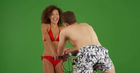 Cute black girl flirting with young male bachelor on bike on green screen Stock Footage