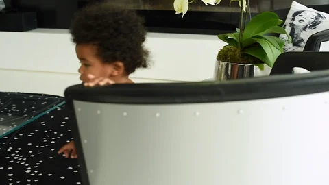 Cute black infant boy trying to climb onto chair. Stock Footage 89044248