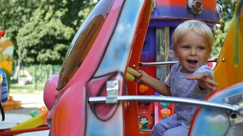 Cute blond 1,5 years old baby boy experiencing joy on carousel Stock Footage 93314636