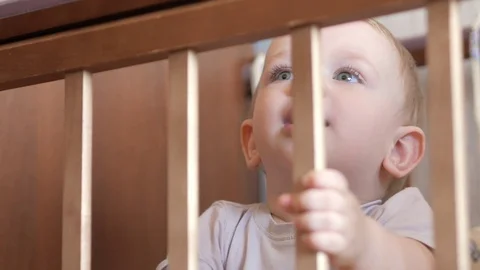 Cute blond babe shows playing in a baby crib with a bolt. He smiles and twists Video stock 75054550