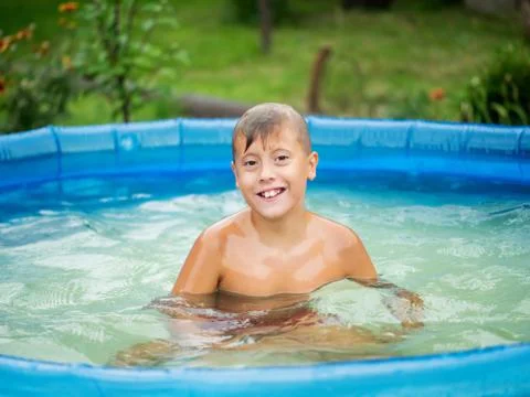 Cute blond boy bathing in a small pool Stock Photos