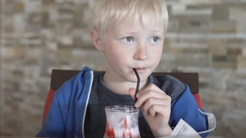 Cute blond boy drinking strawberry milkshake Stock Footage 106872362