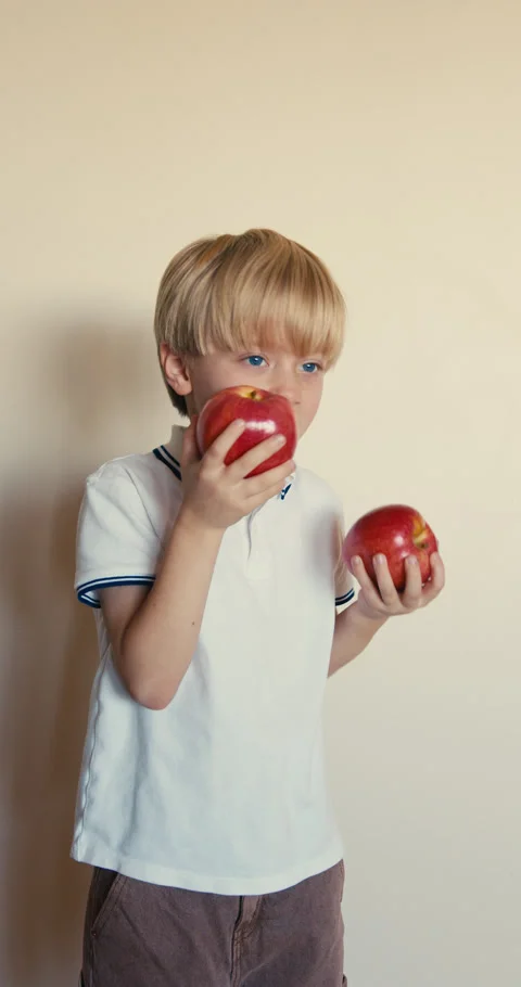 Cute blond boy eating a red apple Stock-Footage 346983370