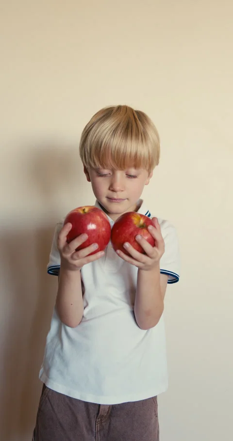 Cute blond boy holding two red apples Video stock 346983358