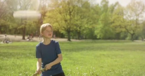Cute blond boy is playing baseball with a wooden stick outside Stock Footage 77612802