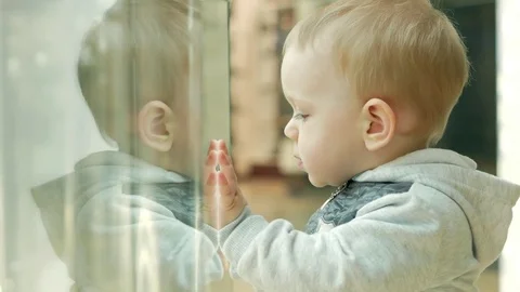 A cute blond boy of two years is considering a store through the glass. The kid Video stock 75052503