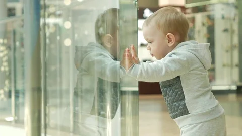 A cute blond boy of two years is considering a store through the glass. The kid Stock Footage 75052807