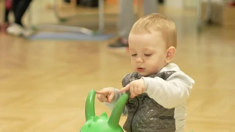 Cute blond boy two years old jumping on an inflatable horse in the mall Video stock 75053377