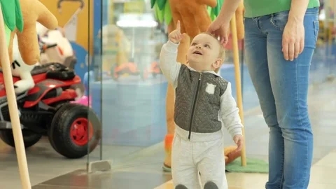 Cute blond boy of two years shows mom big soft toys in the mall at the store Video stock 75053654