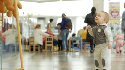 Cute blond boy of two years shows mom big soft toys in the mall at the store Stock Footage 75053776