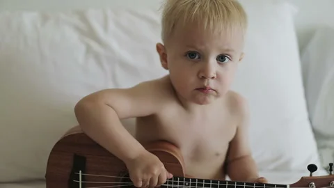 Cute blond child playing ukulele. Stock Footage 94582988