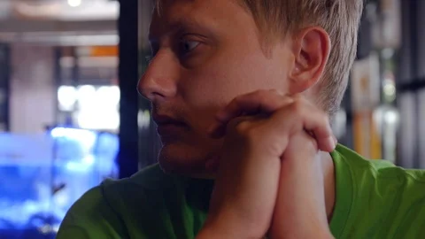 A cute blond man sitting alone in a cafe waiting for his order, looks around. 4k Stock Footage 88800284