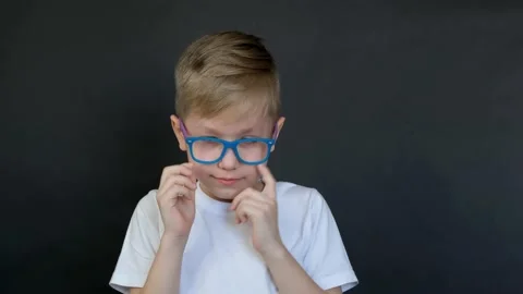 Cute blond school boy in glassed, rubbing eyes, strained eyesight, dark Stock Footage 174817469