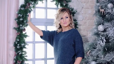 Cute blonde model posing near window and christmas tree. 스톡 동영상 84076723