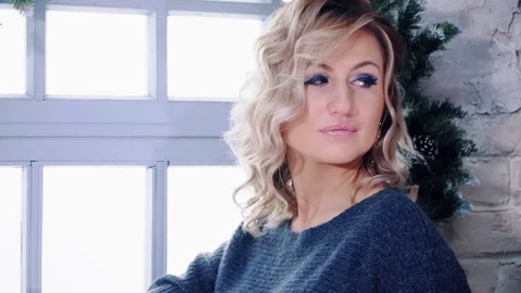 Cute blonde model posing near window and christmas tree. 스톡 동영상 84076752