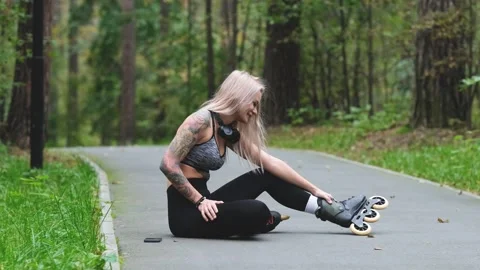 Cute blonde puts on roller skates. She feels free and light while roller skating Stock Footage 305396230