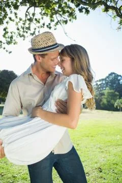 Cute blonde smiling while being lifted by boyfriend in the park Stock Photos