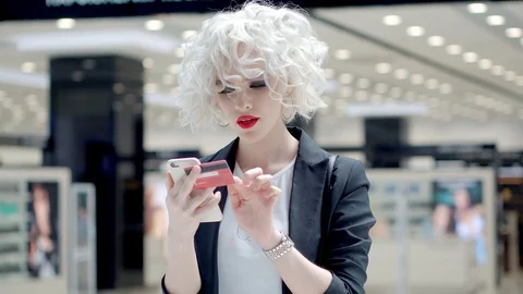 Cute blondie with cell doing payments 스톡 동영상 85986758