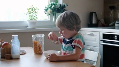 Cute boy 4 years old having breakfast cornflakes with milk at the table at home. Vidéo 111246292