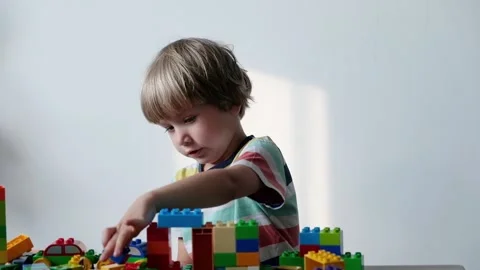 Cute boy 4 years old playing with colorful plastic toy bricks at the table at 動画素材 111366645