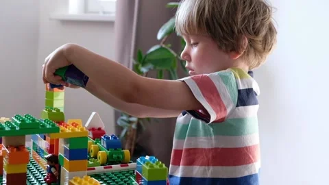 Cute boy 4 years old playing with colorful plastic toy bricks at the table at Vídeos de archivo 111367349